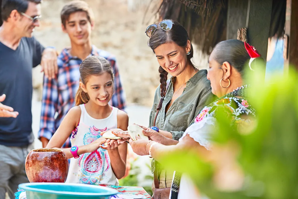 a girl take a taco from a street vendor while in mexico with her family