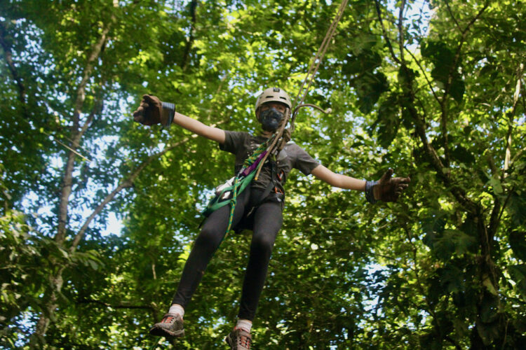 A girl goes hands-free on a tarzan swing in the jungle near quepos, costa rica.