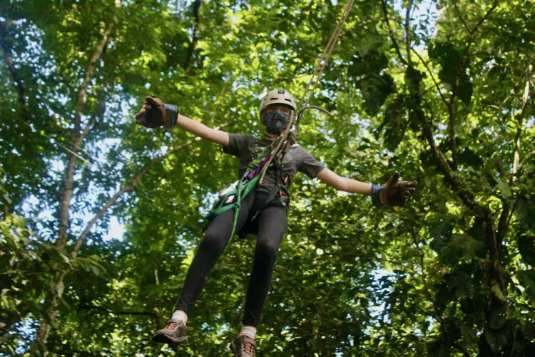 a girl goes hands-free on a tarzan swing in the jungle near quepos, costa rica.