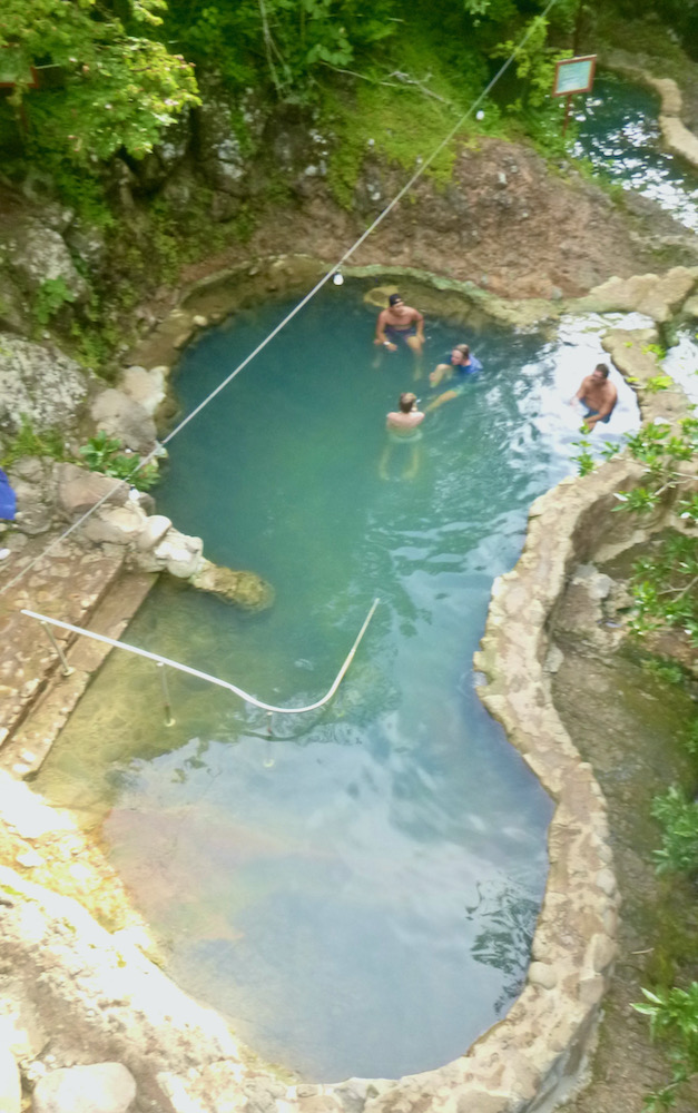 People soak in the volcanic hot springs at hacienda guachpelin