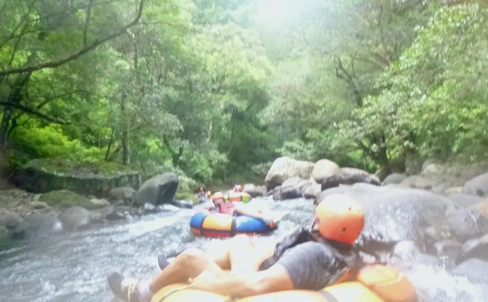 people in helmets go tubing through class 3 rapids with guachipelin adventure center