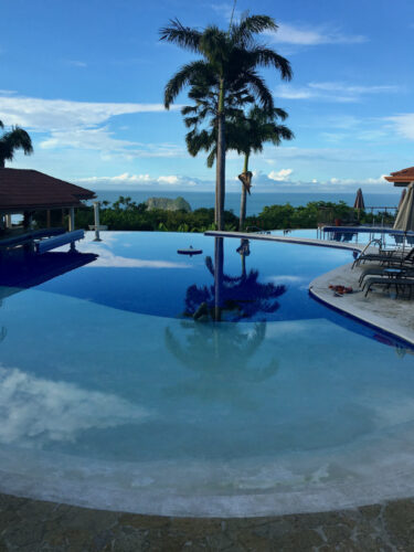The infinity pool at parador resort in costa rica looks out over the jungle and the pacific ocean.