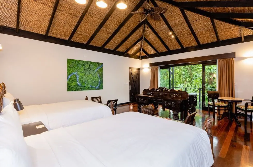 rio celeste hideway's rooms are big with two beds, dark woods and full-length windows that open onto a porch and green forest