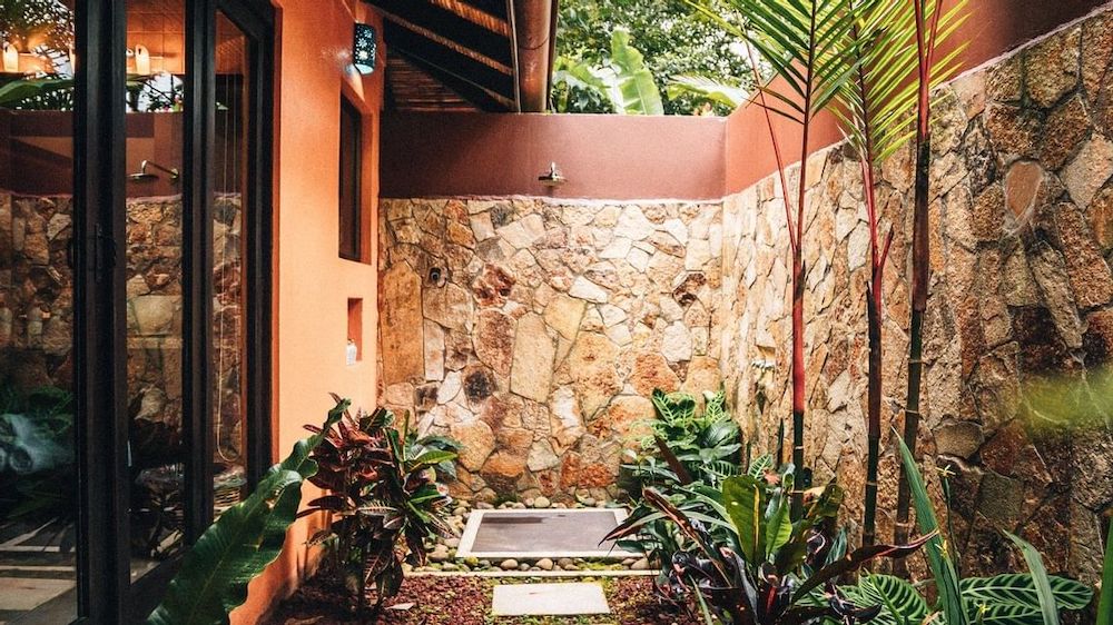 Rio celeste hideaway's rooms have outdoor showers set with a small yard with tall stone walls and greenery.