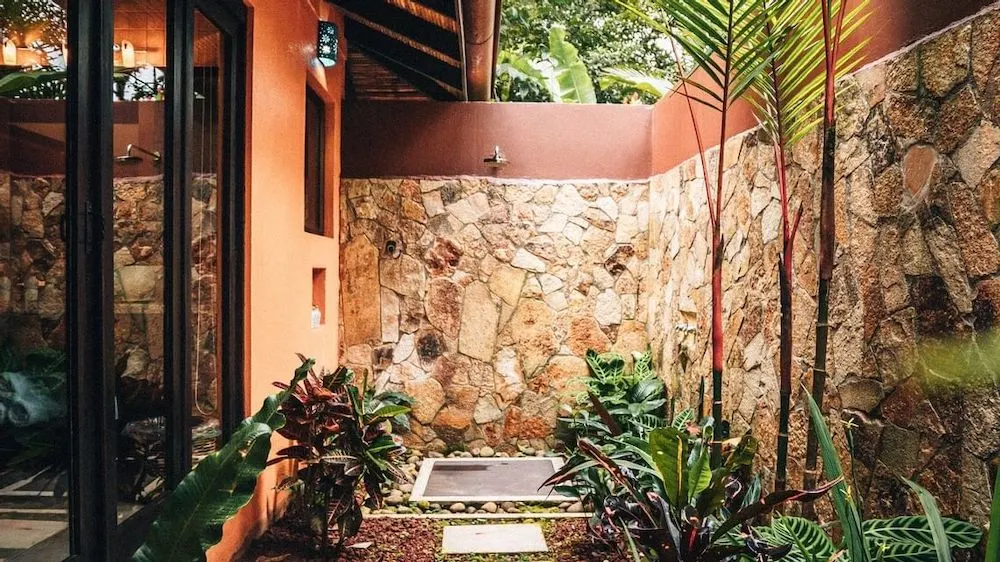 rio celeste hideaway's rooms have outdoor showers set with a small yard with tall stone walls and greenery.