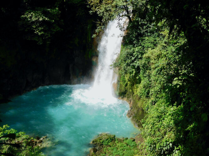 a sky blue waterfall from rio celeste in tenorio volcano national park.