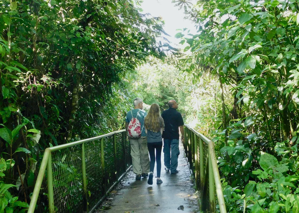 a dad, daughter and guide admire the plants and trees along the path in tenorio volcano national park