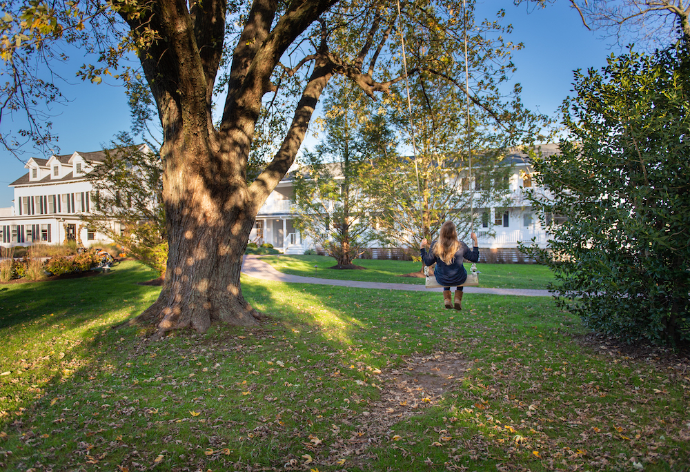 A girls swings on a tree swing on the lawn of the white clapboard wylder hotel