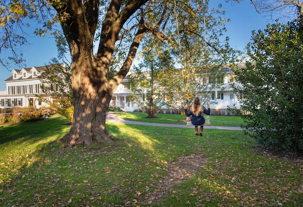 a girls swings on a tree swing on the lawn of the white clapboard wylder hotel