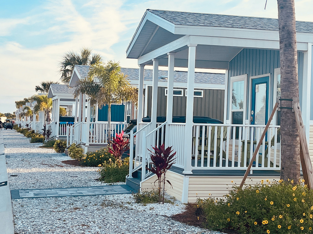 a row of blue and white cabana cabins with porches, flagsone walkways, driveways and porches at camp margaritaville, in auburn, fl