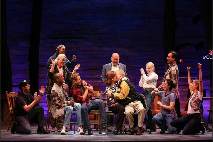 A couple kisses as the ensemble cheers in come from away, one of the best broadway shows for all ages.