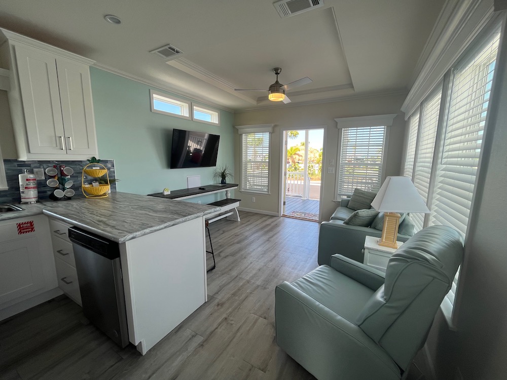 The bright beachy white and sea-green interior of our margaritaville caban cabin includes a compact modern kitchen and a living room with a lot of natural light