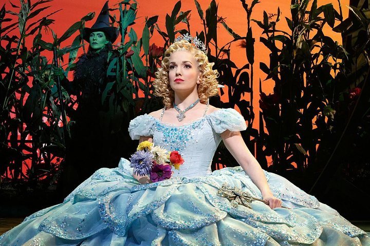 glynda contemplates while elphaba looks on from a corn field in wicked, a broadway show with a strong teen sensibility.