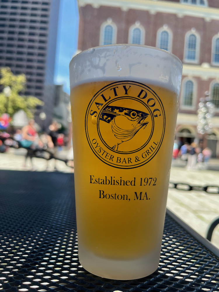 A pint of draft beer with quincy market in the background