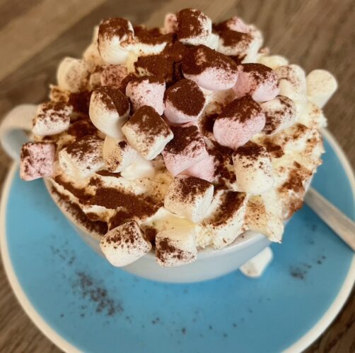 A cup of hot chocolate at fitzbillie's café comes topped with whipeed cream, cocoa powder and pink and white mini-marshmallows.