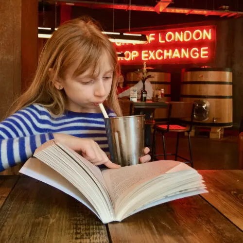 a tween girl sips a shake from its metal mixing cup at brewdog pub in london.