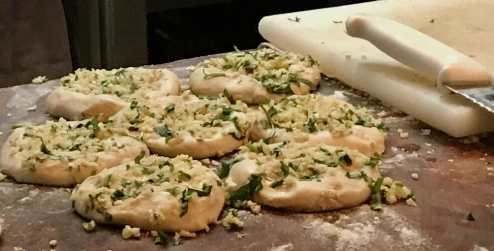 indian breads topped with scallions and cheese are ready for the oven at dishoom bombay café on carnaby street.