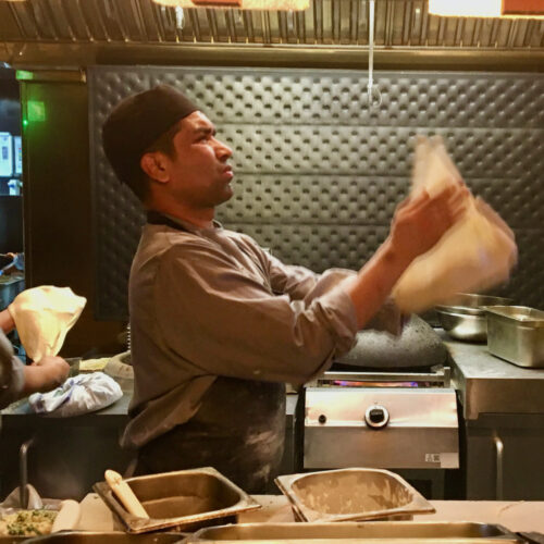 a sous chef tosses bread dough at dishoom indian restaurant in london.