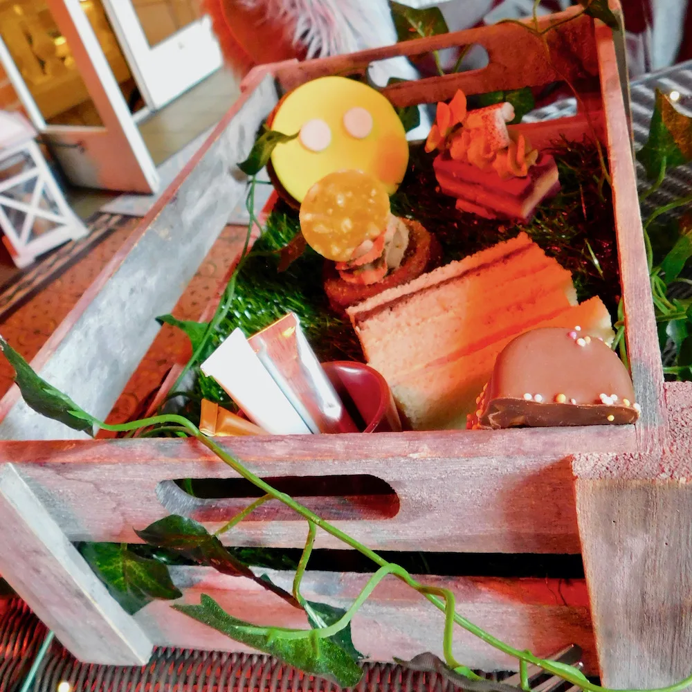 the kids afternoon tea at st. ermins has a garden theme. the small wooden crate includes small sandwiches, chocolate cake and a cookie kids can decorate.