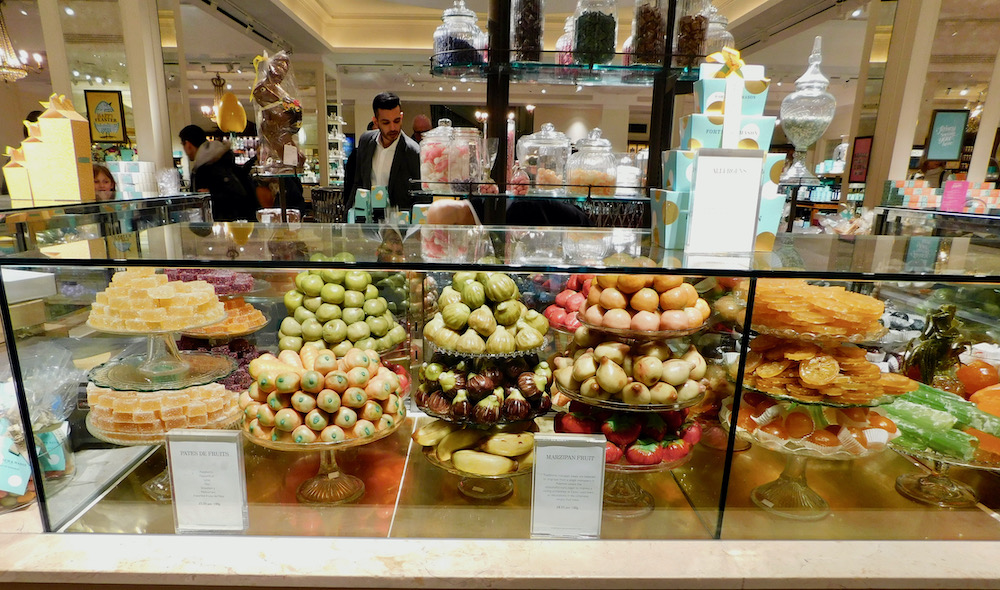 A display case at fortnum & mason shows perfect marzpan fruits, turkish delights and other fancy candies.