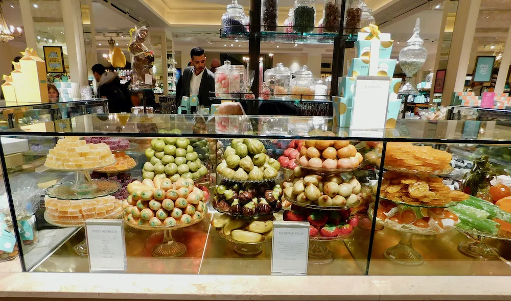 a display case at fortnum & mason shows perfect marzpan fruits, turkish delights and other fancy candies.