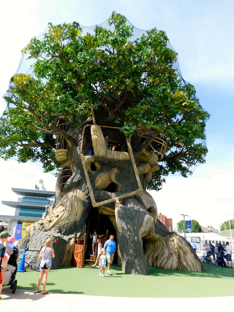 a giant tree full of sports equipment is the centerpiece of an outdoor exhibit at the childrens museum of indianapolis.