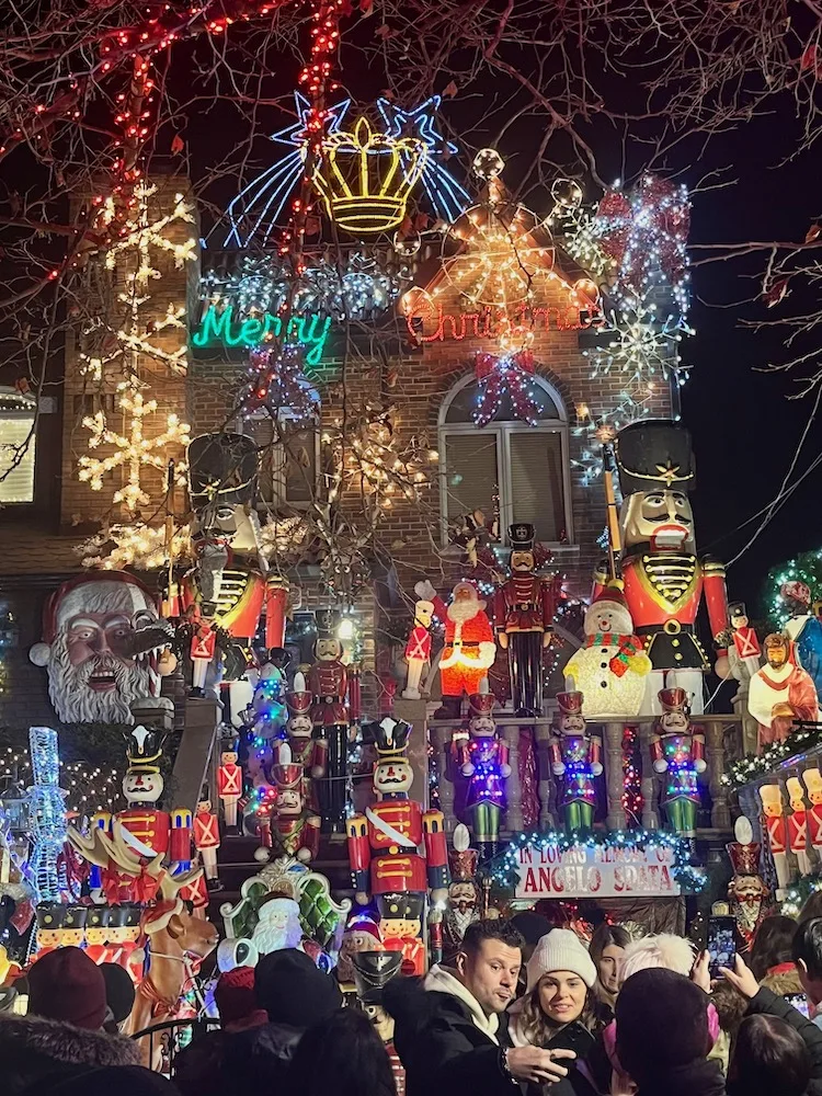 people take photos in front of one of the most popular and most lavishly decorated homes in dyker heights brooklyn at christmastime.