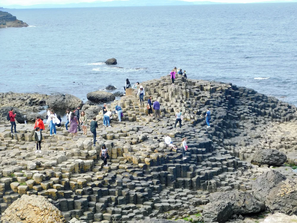 teens love climbing around the giant's causeway, a collection of hexagonal stones that stretch inot the sea in northern ireland.