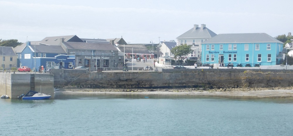 small colorful brick and stone buildings dot the harbor or inish mor, the largest of the aran islands as the ferry approaches.