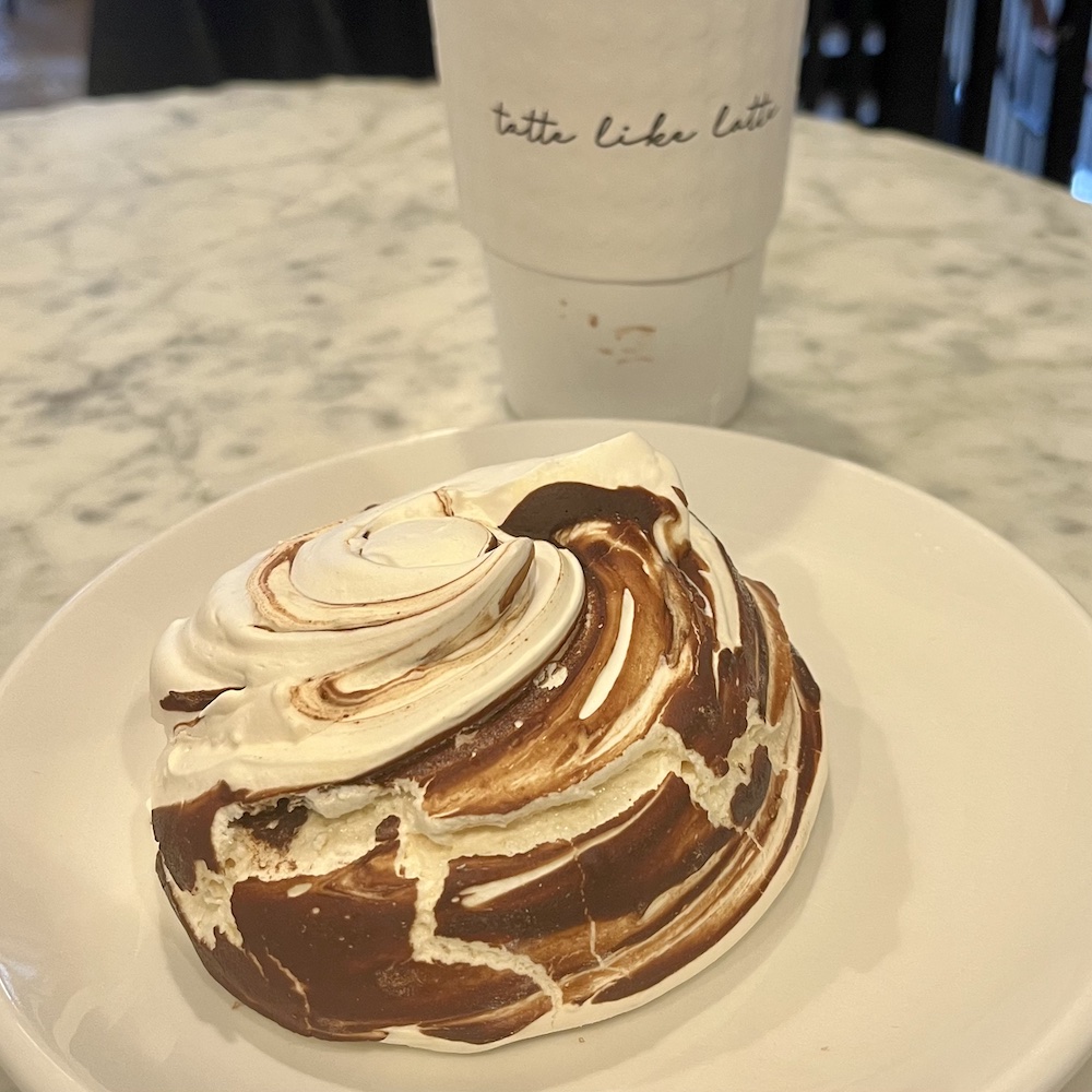 a large fudge-swirled merengue and coffee on one of tatte's marple café tables in boston.