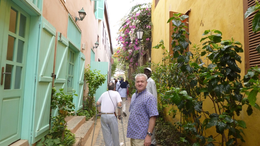an alleyway of colorful pastel building and wooden shutters on ile de gorée off of dakar