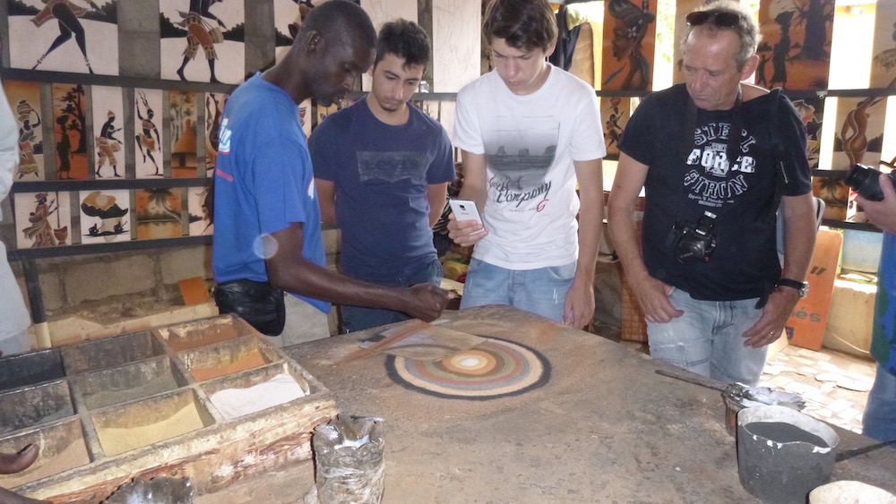 an artist on ile de gorée demonstrates how he makes art with different colors of sand.