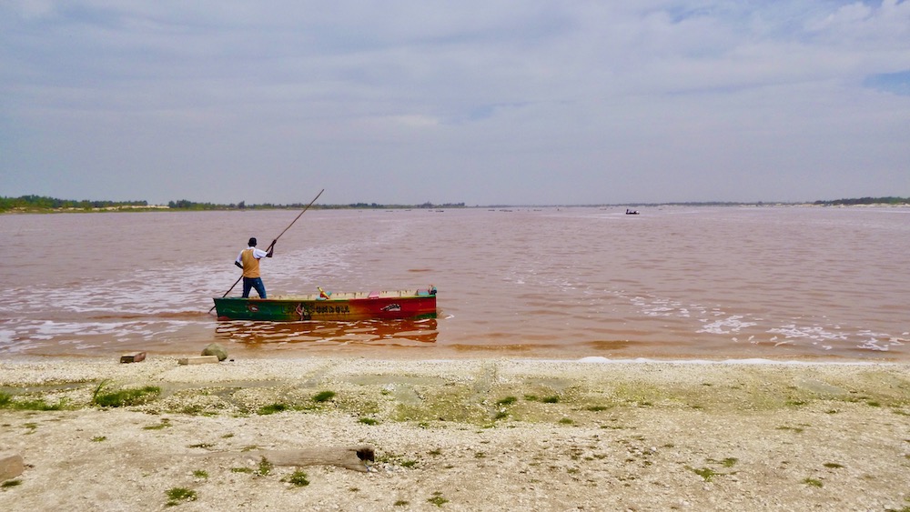 A salt harvester pushes his pirogue around lac rose in senegal