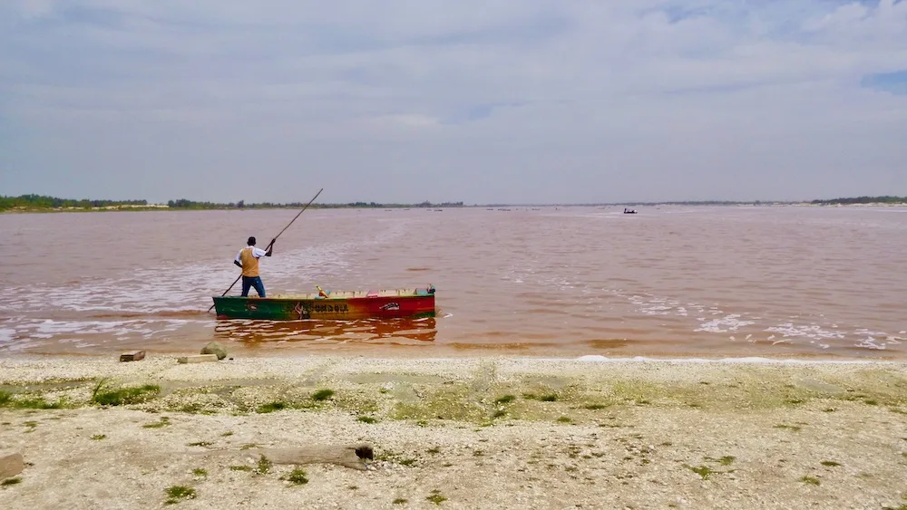 a salt harvester pushes his pirogue around lac rose in senegal