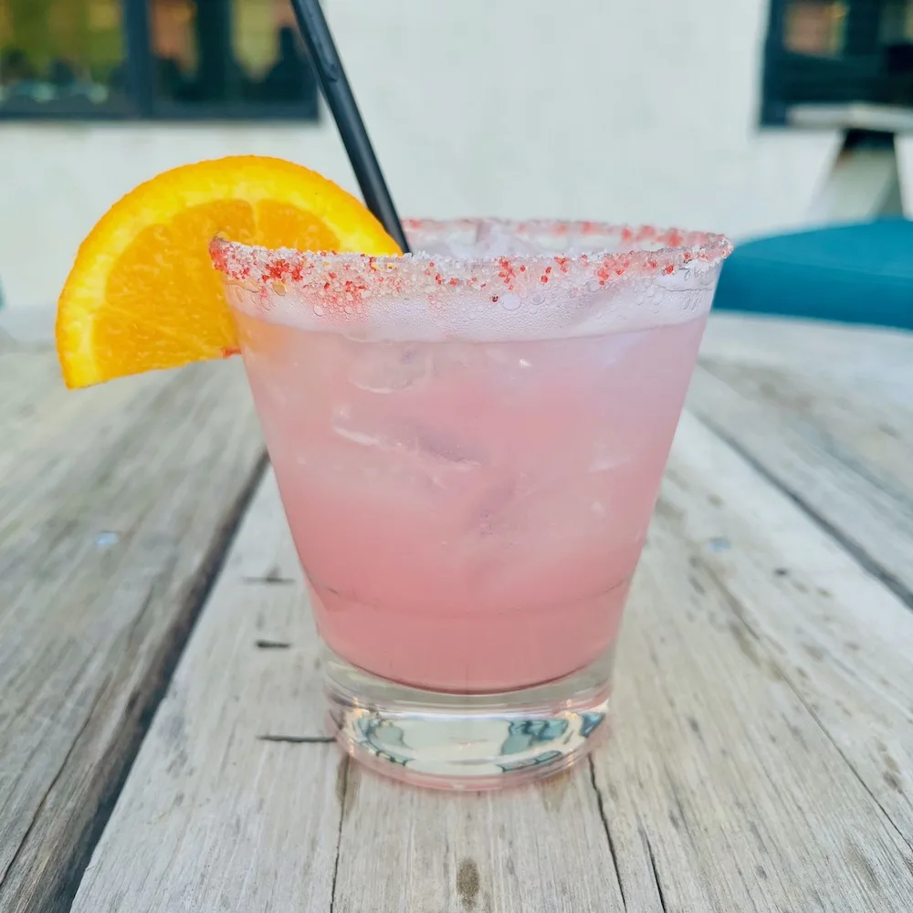 a bright pink cactus-pear margarita with salt and chiles on the rim of the glass.
