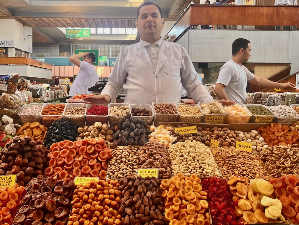 a vendor in almaty's green market sells halva, dried fruit and nuts.