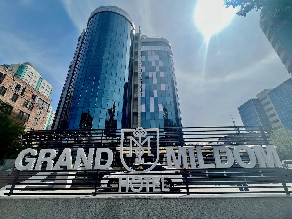 the mirrored exterior of the modern grand mildom hotel in almaty
