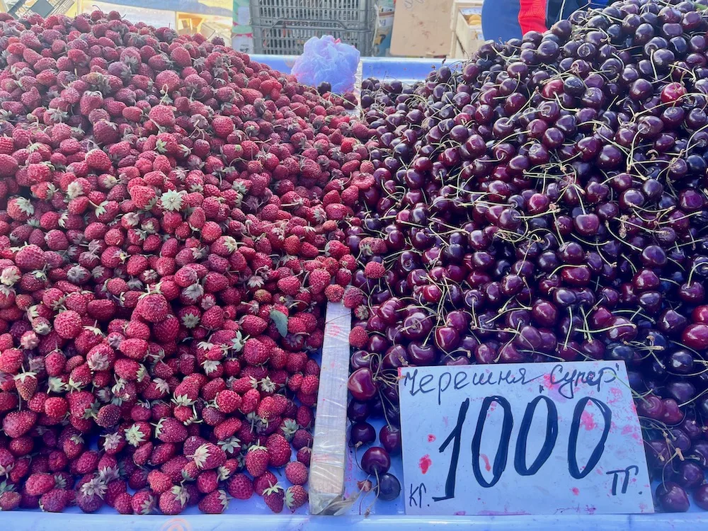 piles of fresh strawberries and cherries at kazakhstan's green bazaar