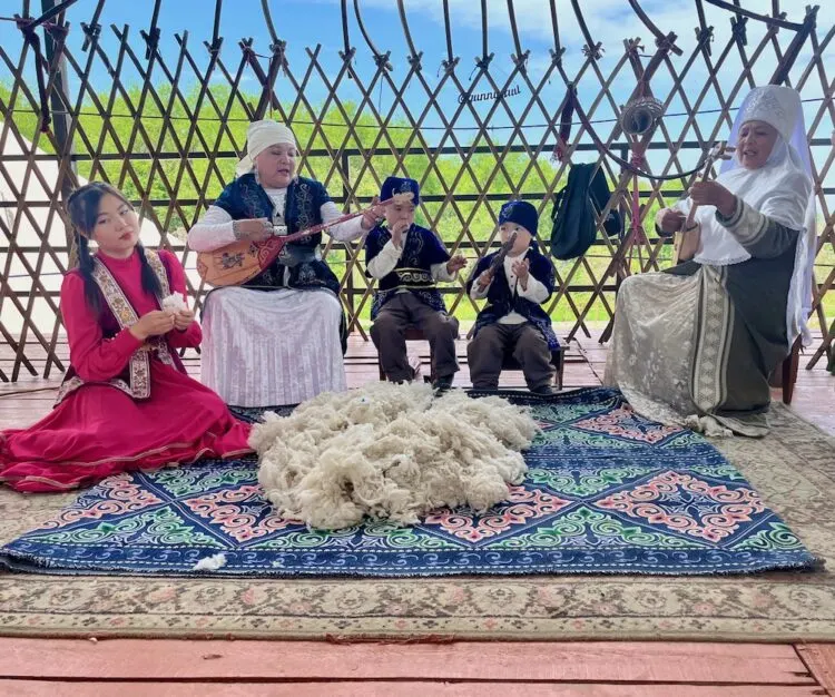 2 women, a girl and two young boys play music on traditional kazakh instruments/