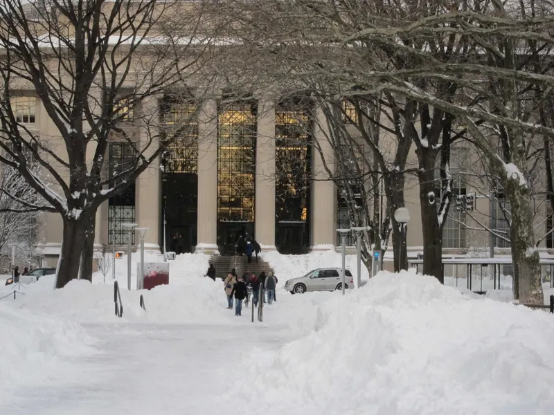 a group of people trudge across a snowy mit campus. touring colleges in winter is a good reality check for spending 4 years in a place.