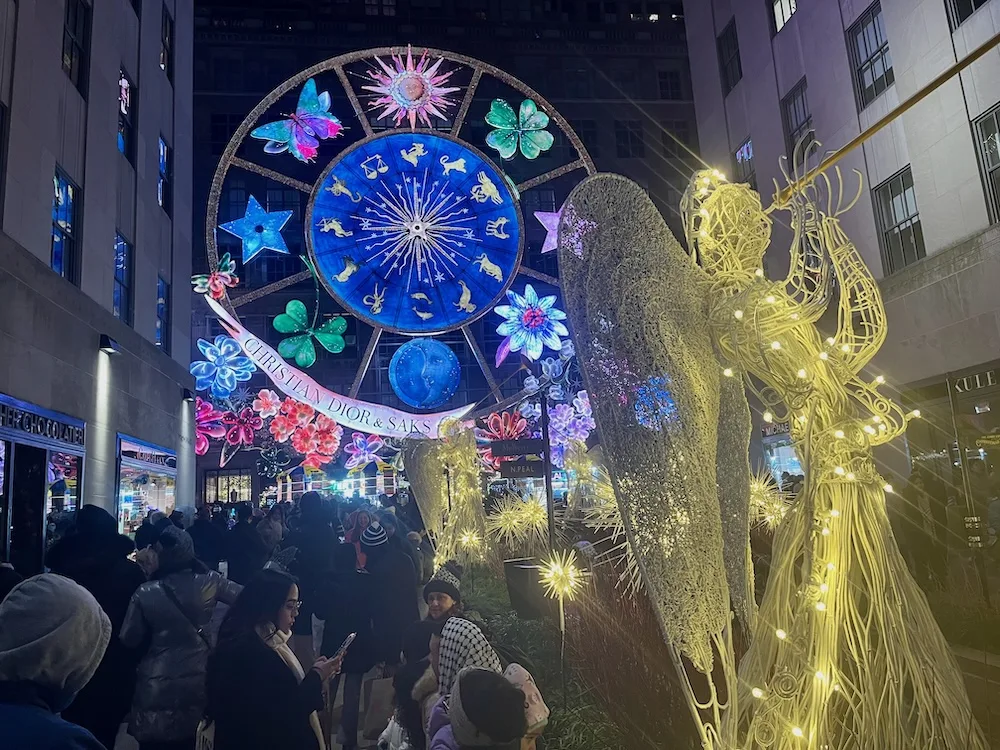 giant christmas lights on the side of saks 5th avenue ny, seen through the rockefeller center angels. 