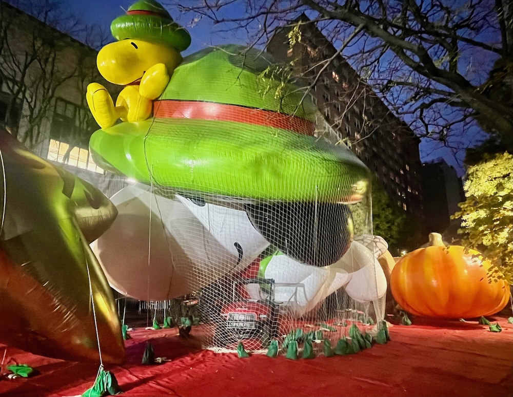 a giant balloon of snoopy and woodstock waits overnight for the thanksgiving day parade in nyc