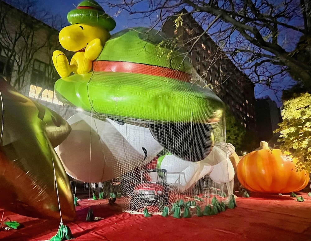A giant balloon of snoopy and woodstock waits overnight for the thanksgiving day parade in nyc