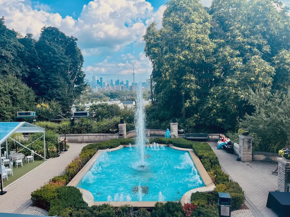 the patio at casa loma has a fountain, places to sit and a gorgeous view of the toronto skyline
