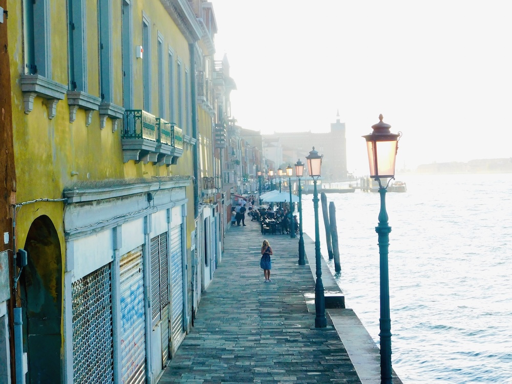 giudecca's promenade at diusk mingles old-fashioned street lamps, brightly colored buildings and church spires.