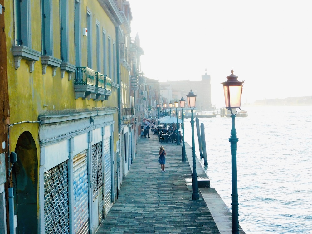 Giudecca's promenade at diusk mingles old-fashioned street lamps, brightly colored buildings and church spires.