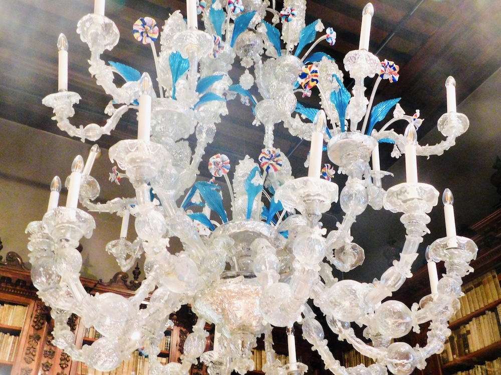 Venice's museum correr has elaborate murano glass chandeliers like this one with white branches, blue leaves and rainbow flowers.