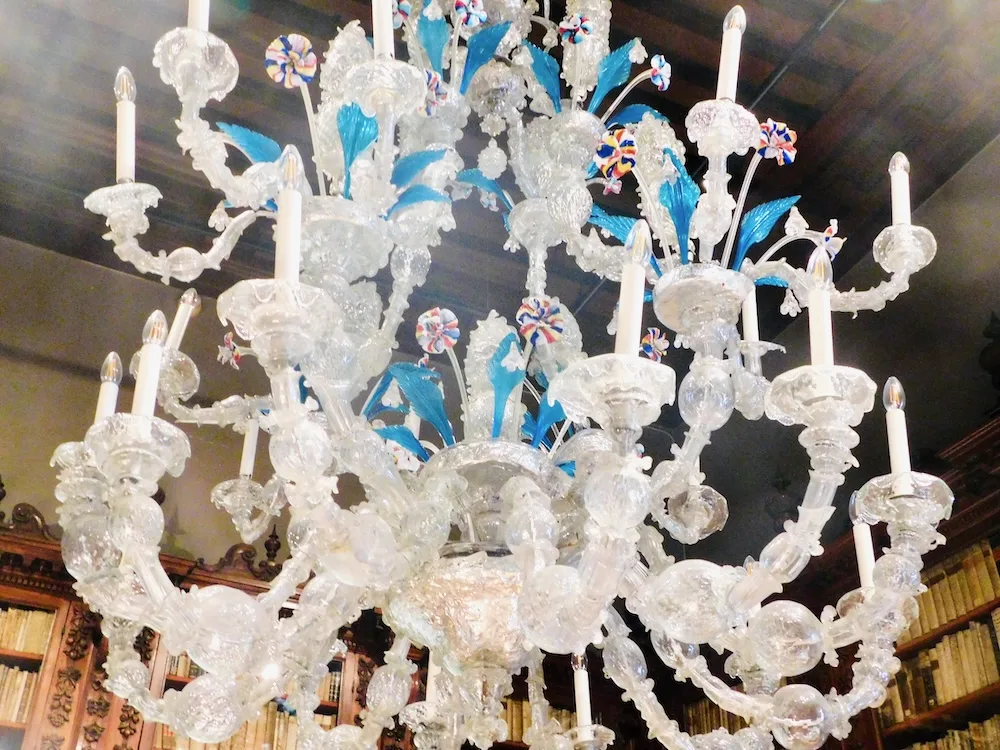 venice's museum correr has elaborate murano glass chandeliers like this one with white branches, blue leaves and rainbow flowers.