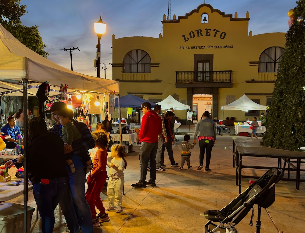 People shop for souvenirs at dusk at stalls set up on loreto's main plaza.