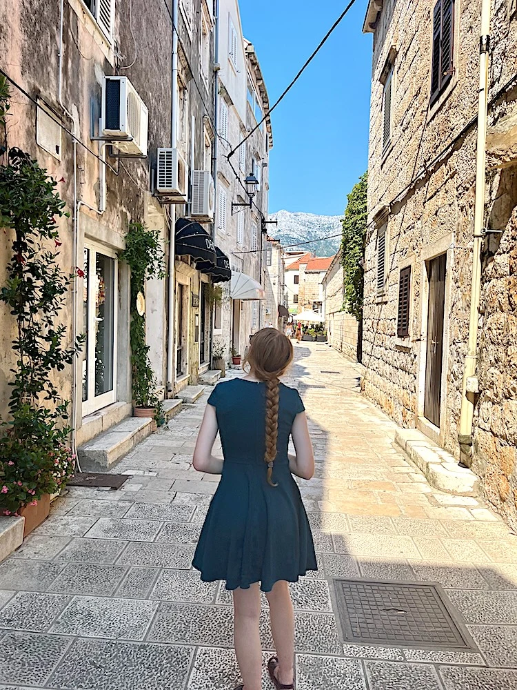 a teen wanders down in stone street, between stone buildings in korcula.